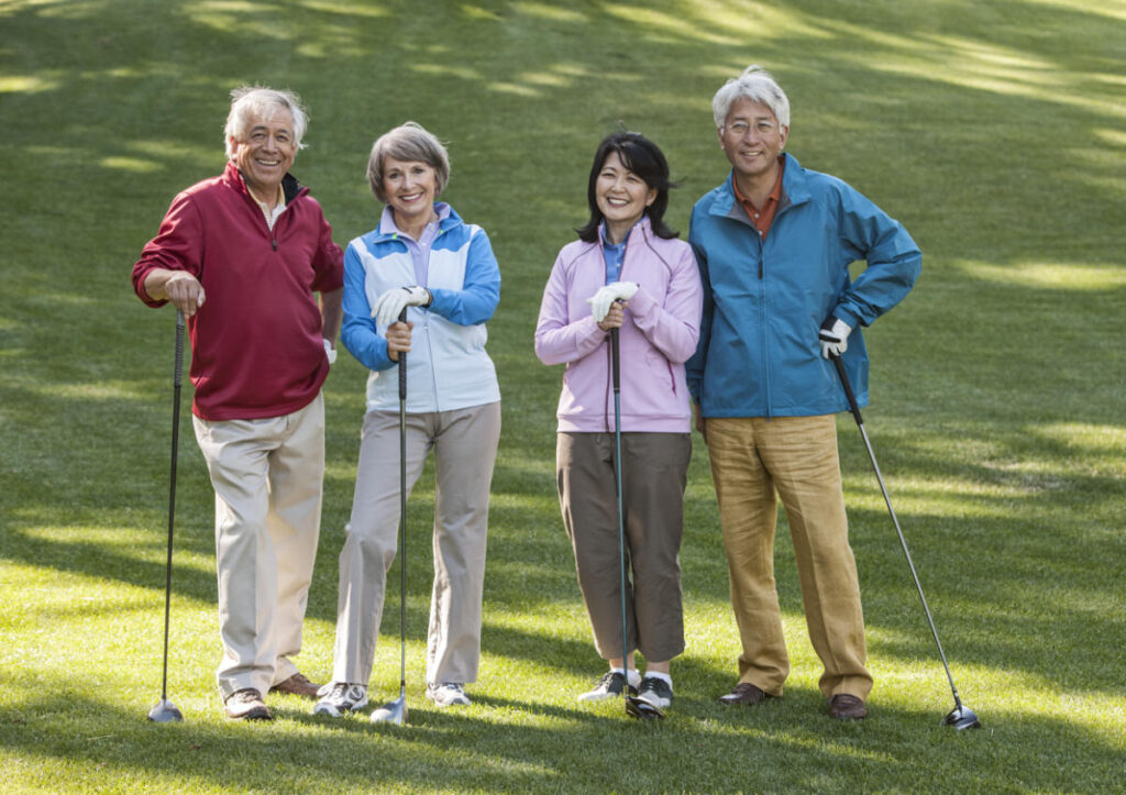 Two young senior golfing couples on the course and ready to play, retirement community, independent living