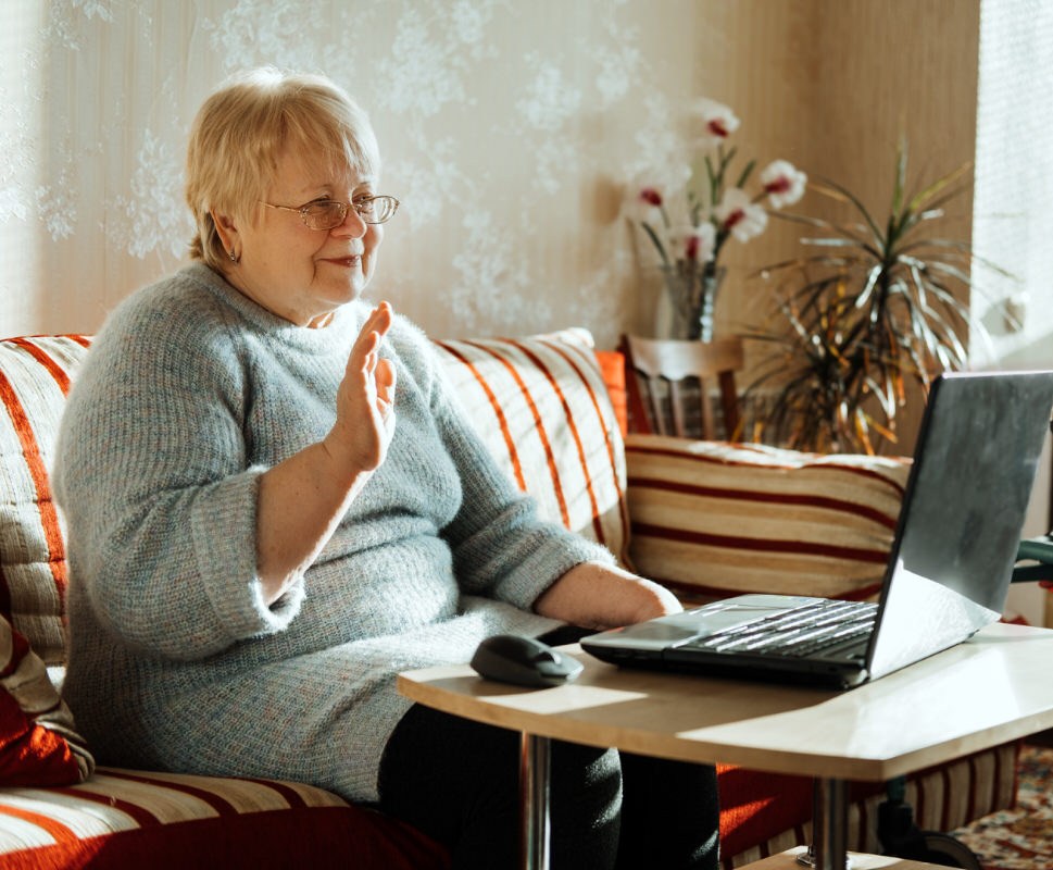 Senior mature candid real Caucasian woman look at laptop screen at home. Happy senior blonde female have online video call with family via internet. Elderly technology concept, independent retirement, senior living community